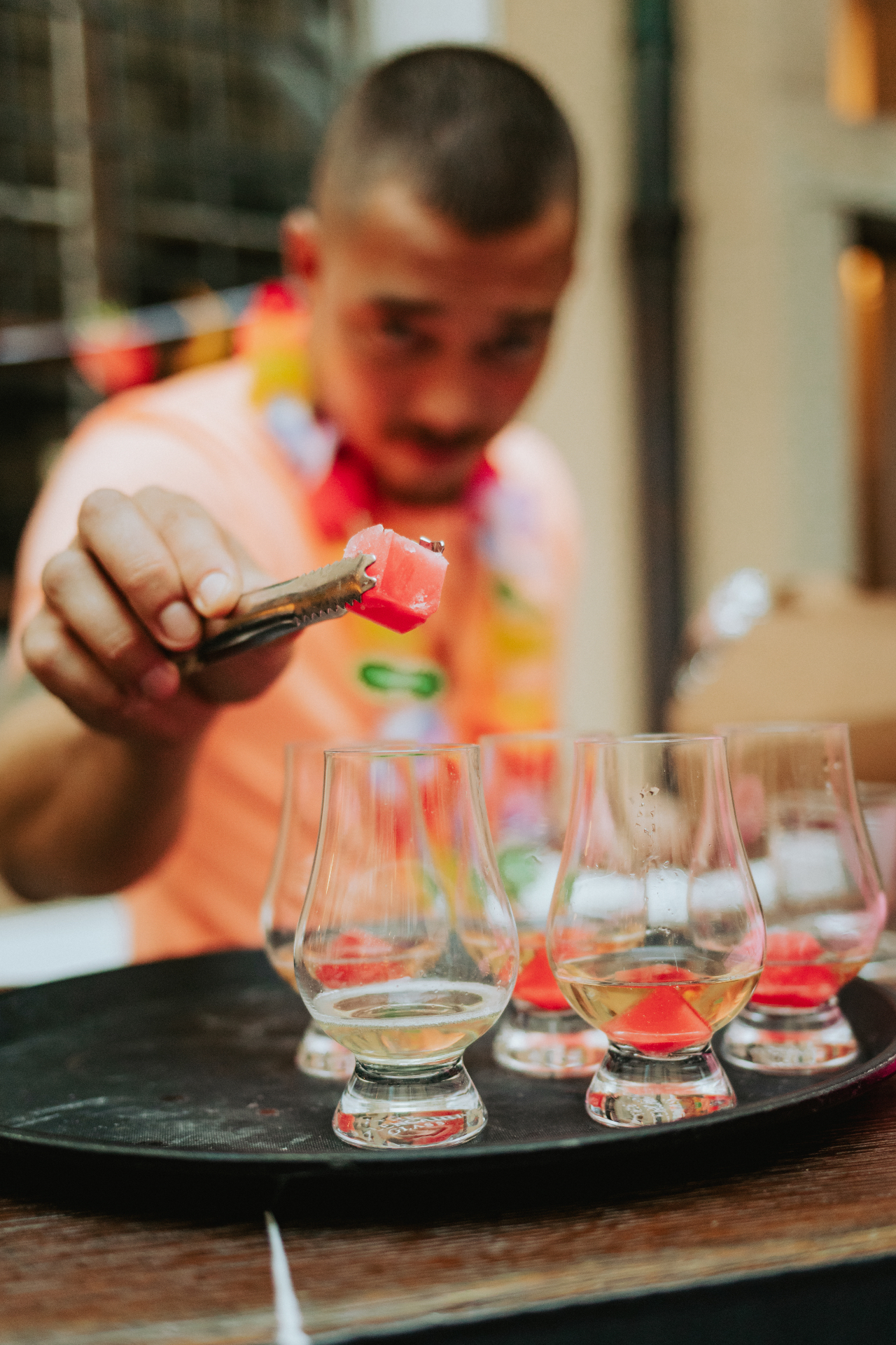 Barman v havajském věnci servíruje ovocné kostky do skleniček s welcome drinkem