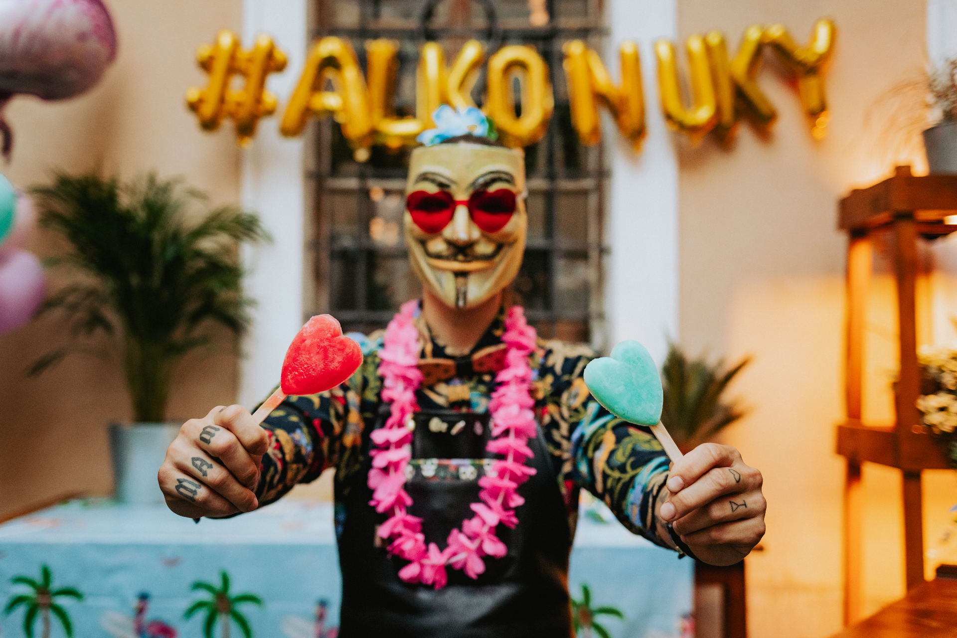 Barman s maskou drží červený a tyrkysový srdíčkový Alkonuk